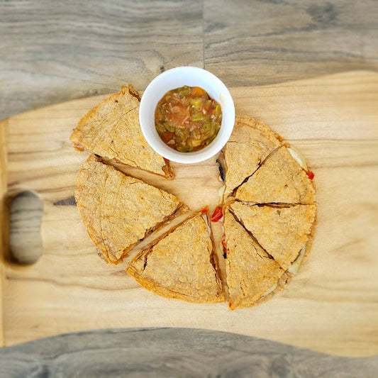 Mushroom Fajita Quesadilla made with our Southwest Tortilla Mix. Sliced and placed on a cutting board with a cup of green chile.