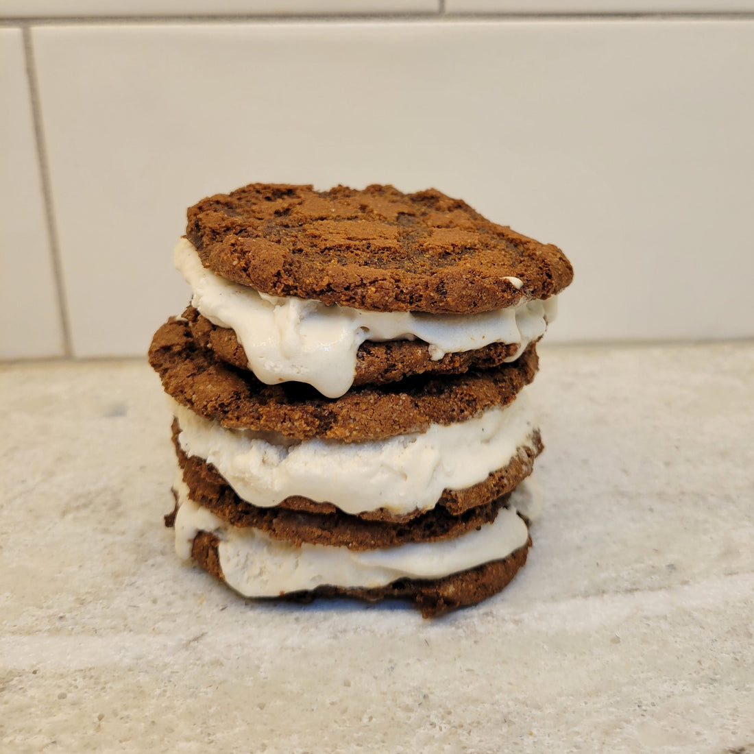 Stack of 3 brownie ice cream cookie sandwiches filled with vanilla ice cream..