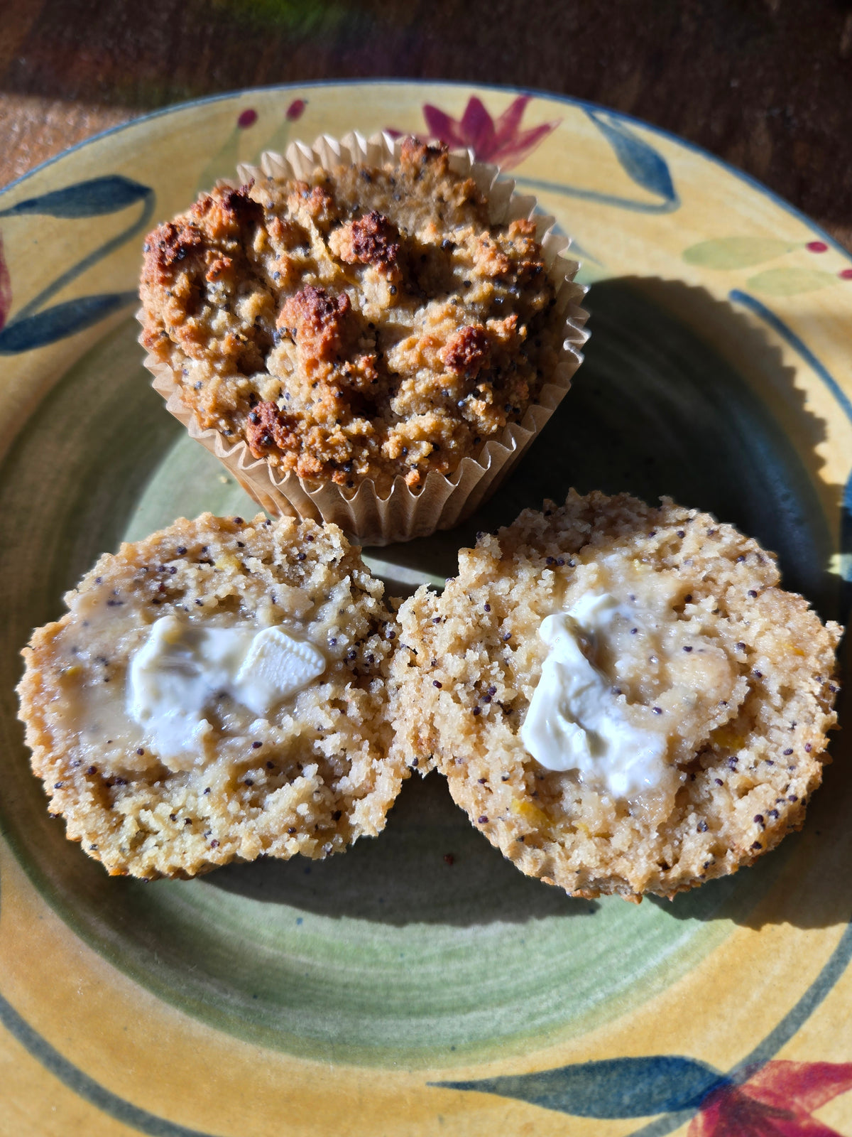 Two muffins on a plate with one cut open with butter melting on each half.
