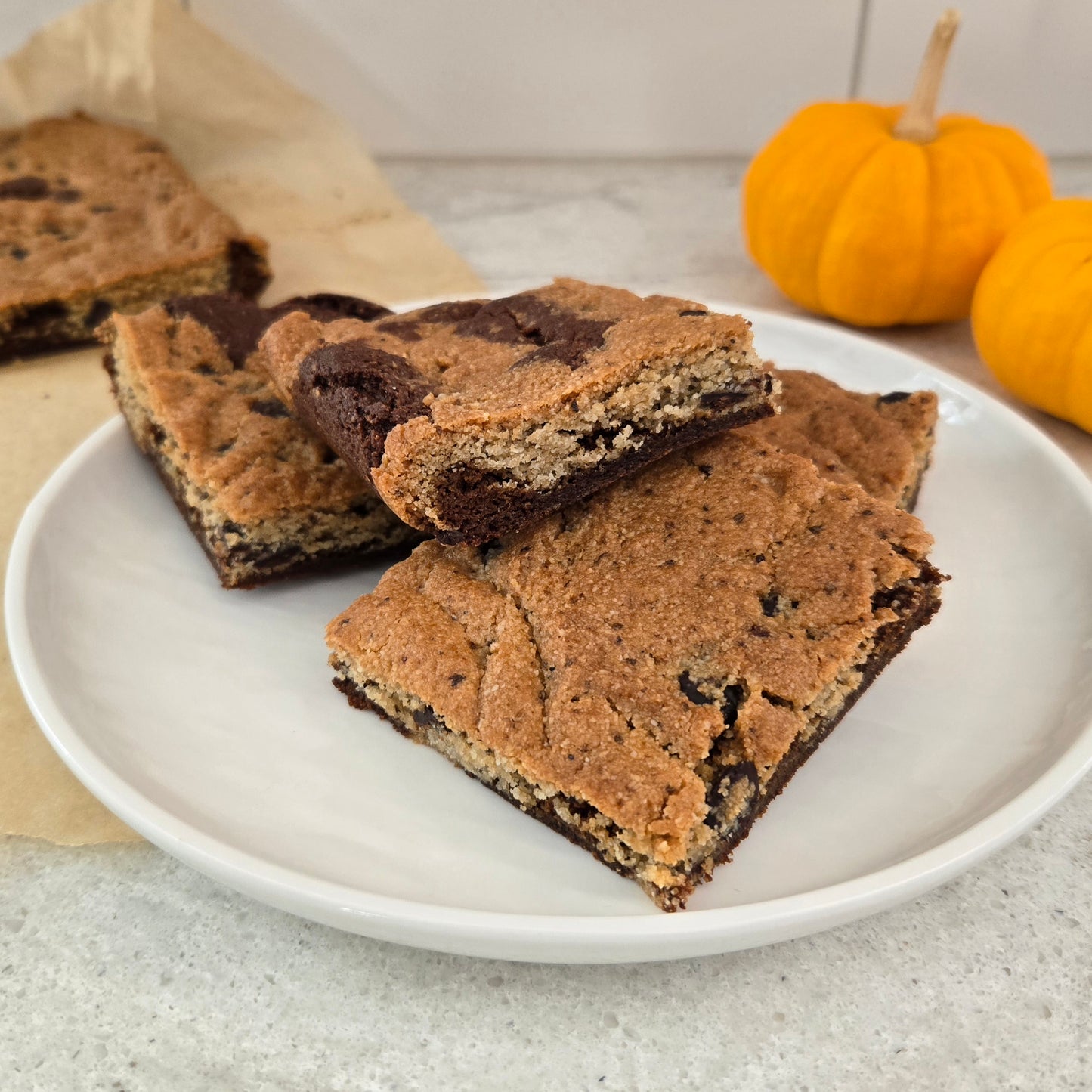 Plate of Pumpkin Spice Brookie bars with pumpkins in the background.
