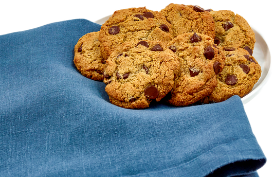 Chocolate chip cookies on a white plate with a blue cloth underneath