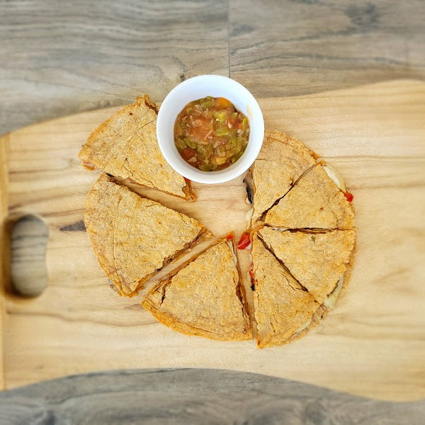 Mushroom Fajita Quesadilla made with our Southwest Tortilla Mix.  Sliced and placed on a cutting board with a cup of green chile.