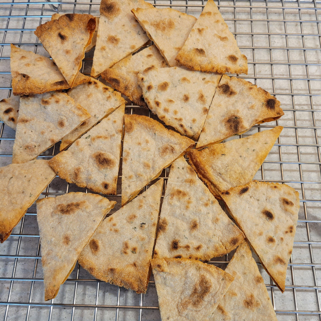 Tortilla chips cooling on a cookie rack.