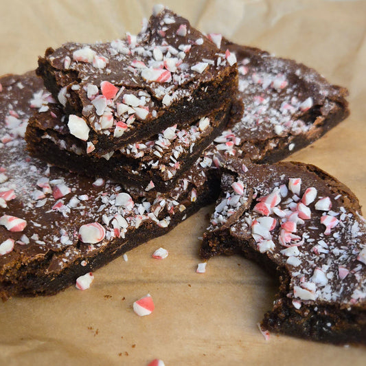 Stack of 4 brownies with crushed candy canes on top with mini candy canes in front of the brownies.