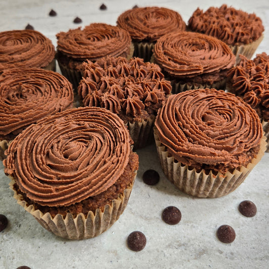 10 frosted chocolate cupcakes on a white background with bite out of one cupcake with sprinkled chocolate chips around. 