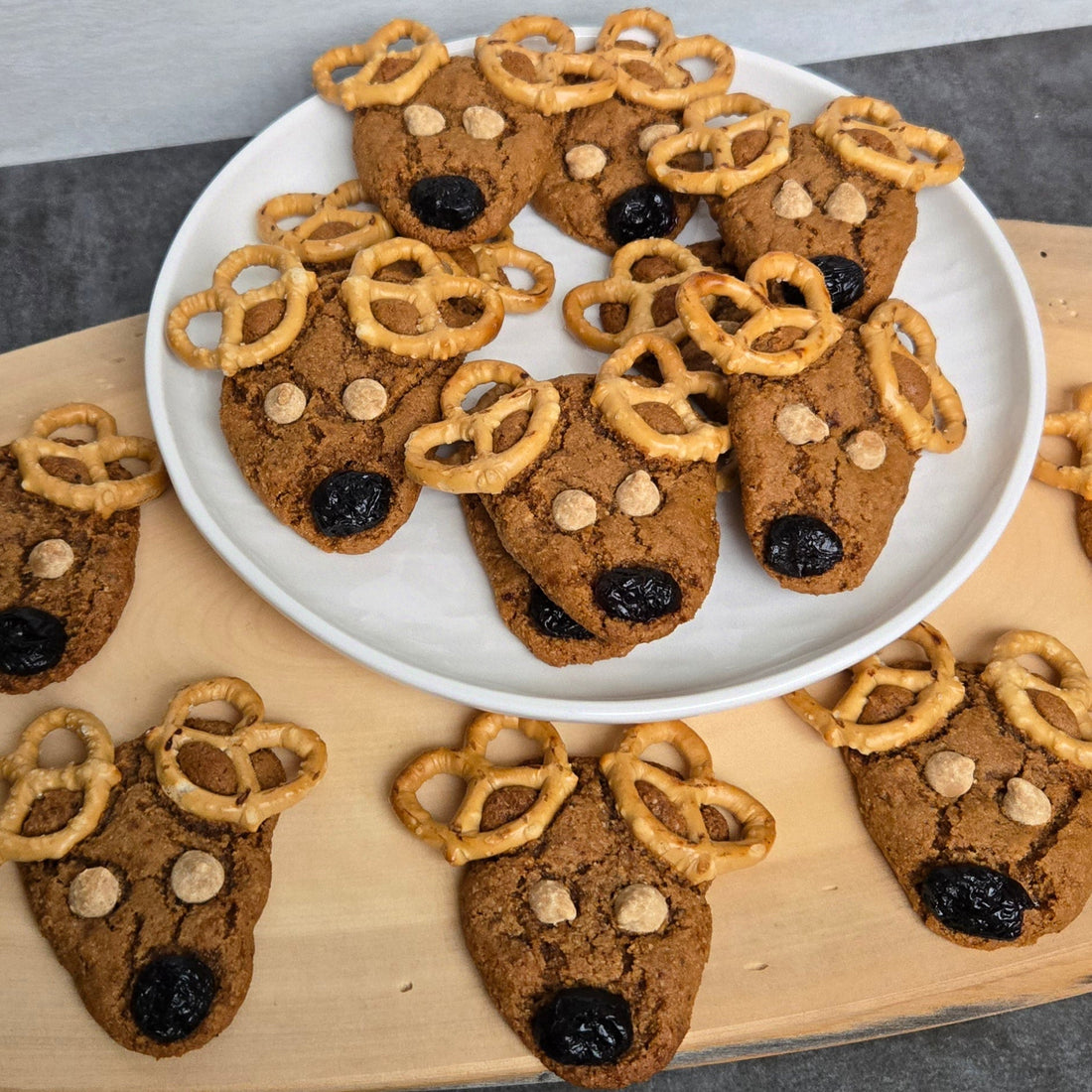 Gingersnap reindeer cookies, made in the shape of a triangle, with pretzel antlers, peanut butter chip eyes and a cranberry nose.