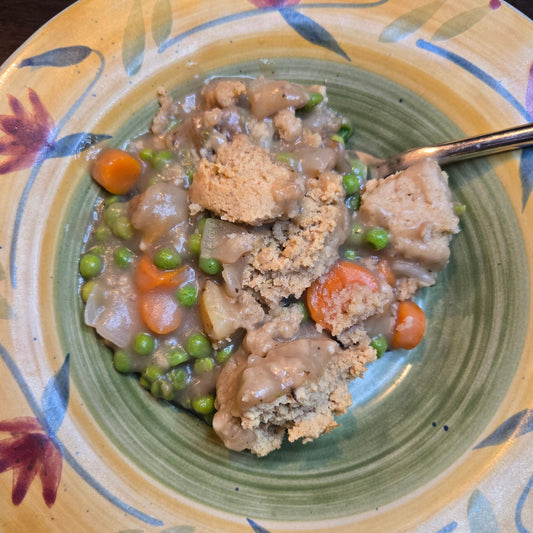 Cassavaberry gluten-free biscuit pot pie in a yellow bowl with red flowers around the sides.