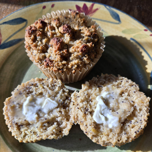 2 muffins on a plate. One whole, and one cut in half with butter on top.