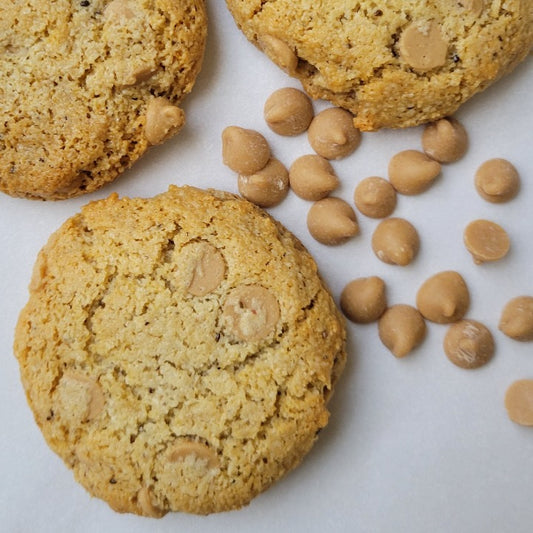 Baked peanut butter chip cookies in a group of three with peanut butter chips next to the cookies.