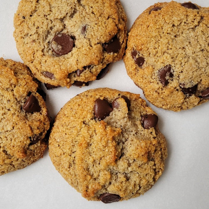 Baked group of four chocolate chip cookies on a white background.