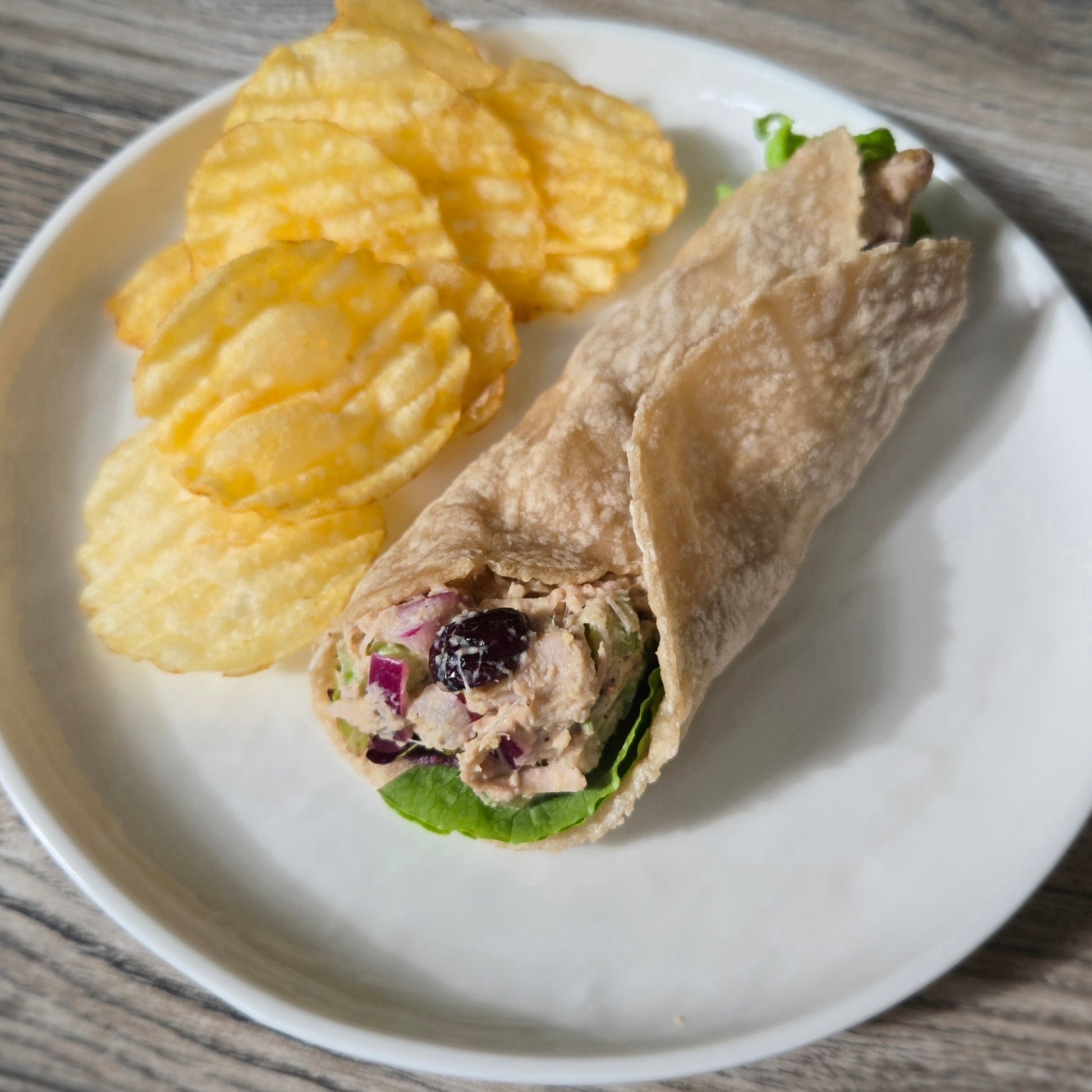 Made from Cassavaberry Tortilla Mix, Jackfruit salad wrap on a plate with potato chips.