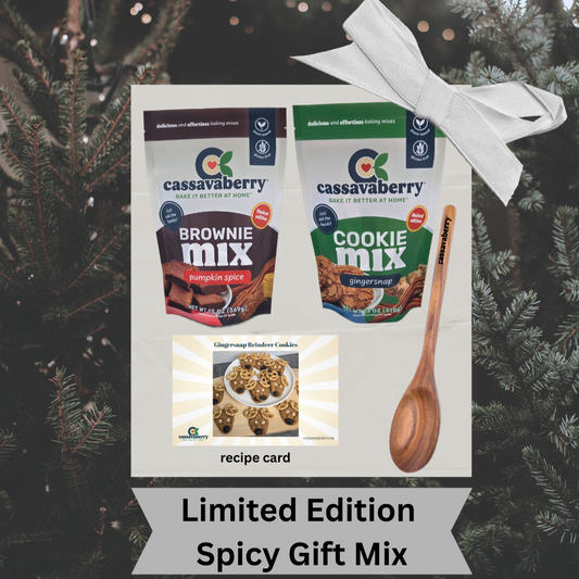 Cassavaberry Brownie Mix and Cookie Mix packages with a Cassavaberry wooden mixing spoon and recipe card to make Gingersnap Reindeer Cookies against a Christmas tree background.