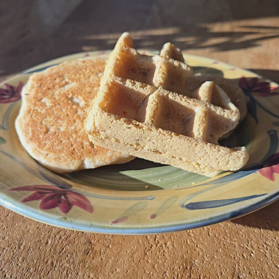 Pouring syrup over a gluten free and vegan pancake and waffle.